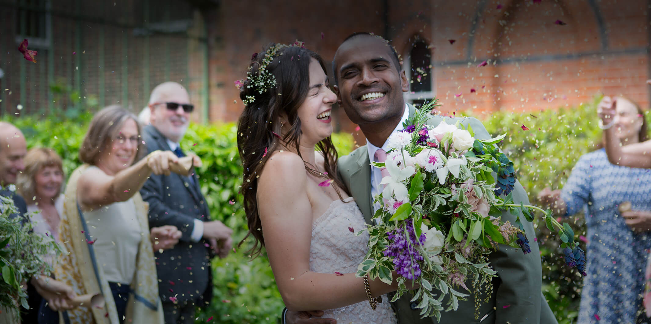 A bride and groom smile while confetti is thrown on them