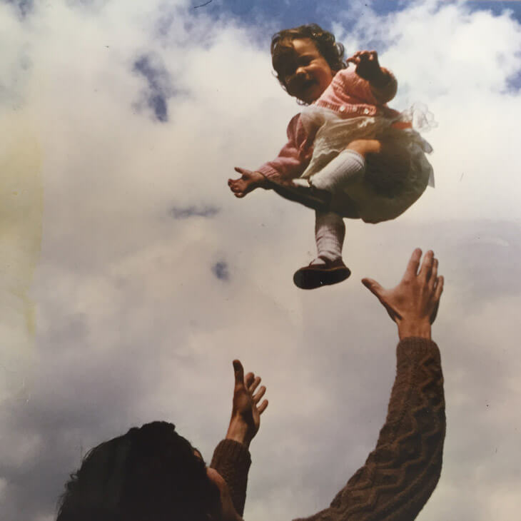 A smiling child being thrown up in the air