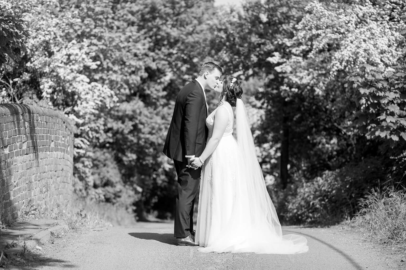 Black and white image of a bride and groom kissing