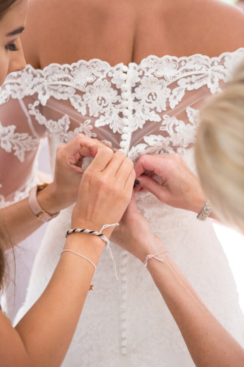 Bride's lace wedding dress being buttoned up