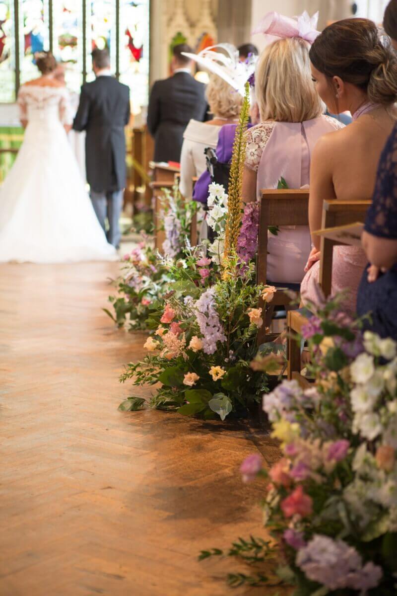 A sea of flowers adorns a church wedding aisle 