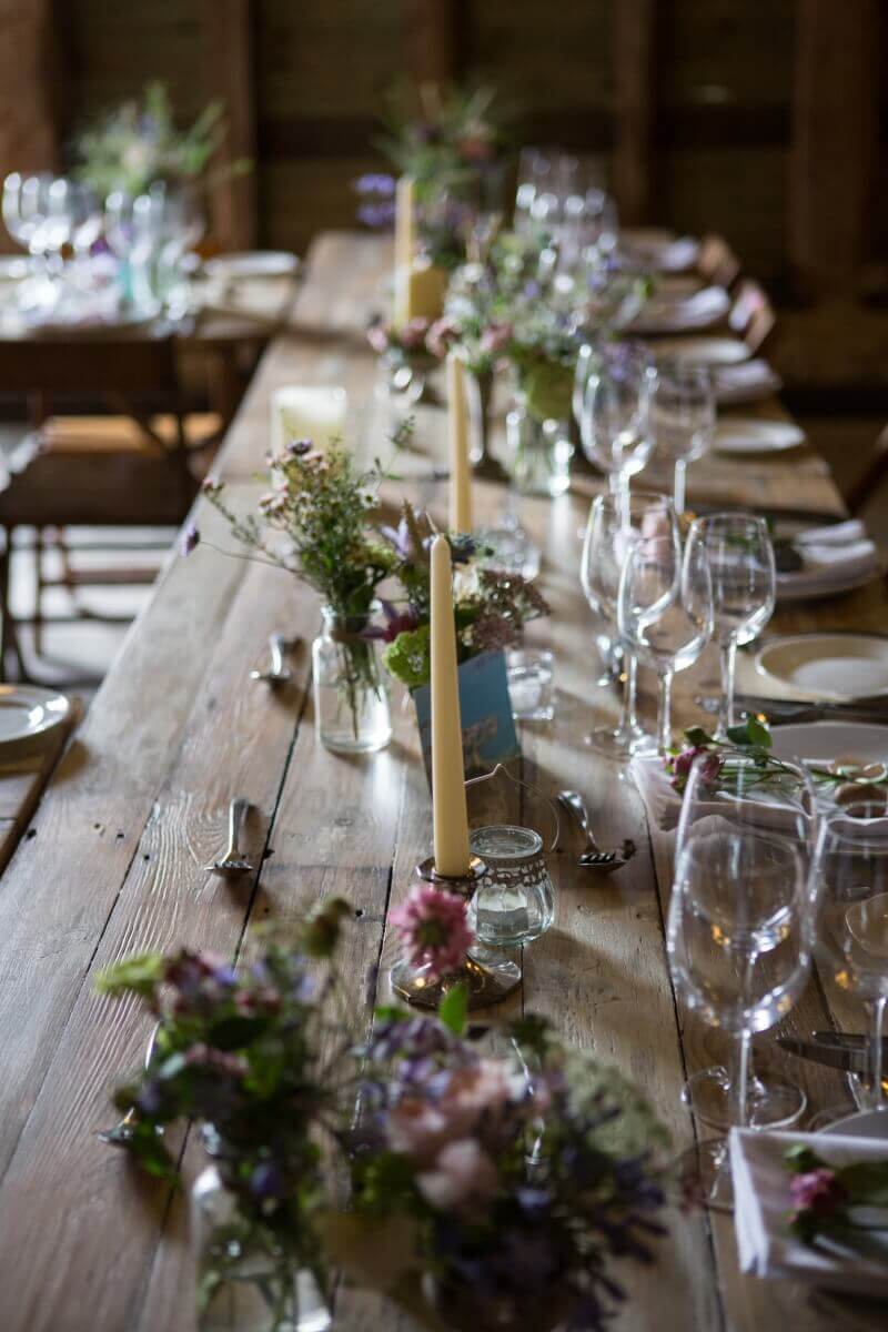 Barn wedding with glasses,flowers and candles on rustic tables