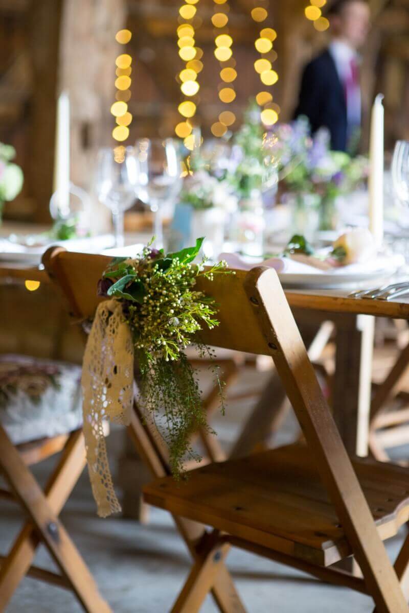 Rustic barn wedding with fair lights and flowers tided to the chairs