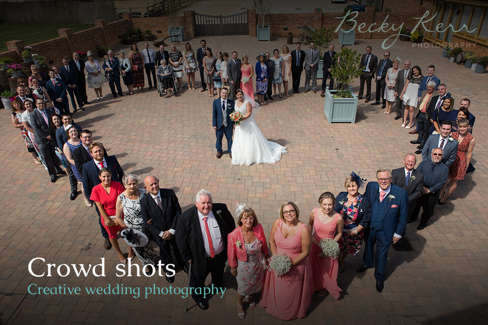 A crowd stood in the shape of a heart as an example of creative wedding photography