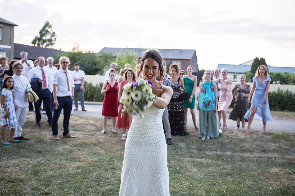 A happy, beautiful bride prepares to toss her bouquet