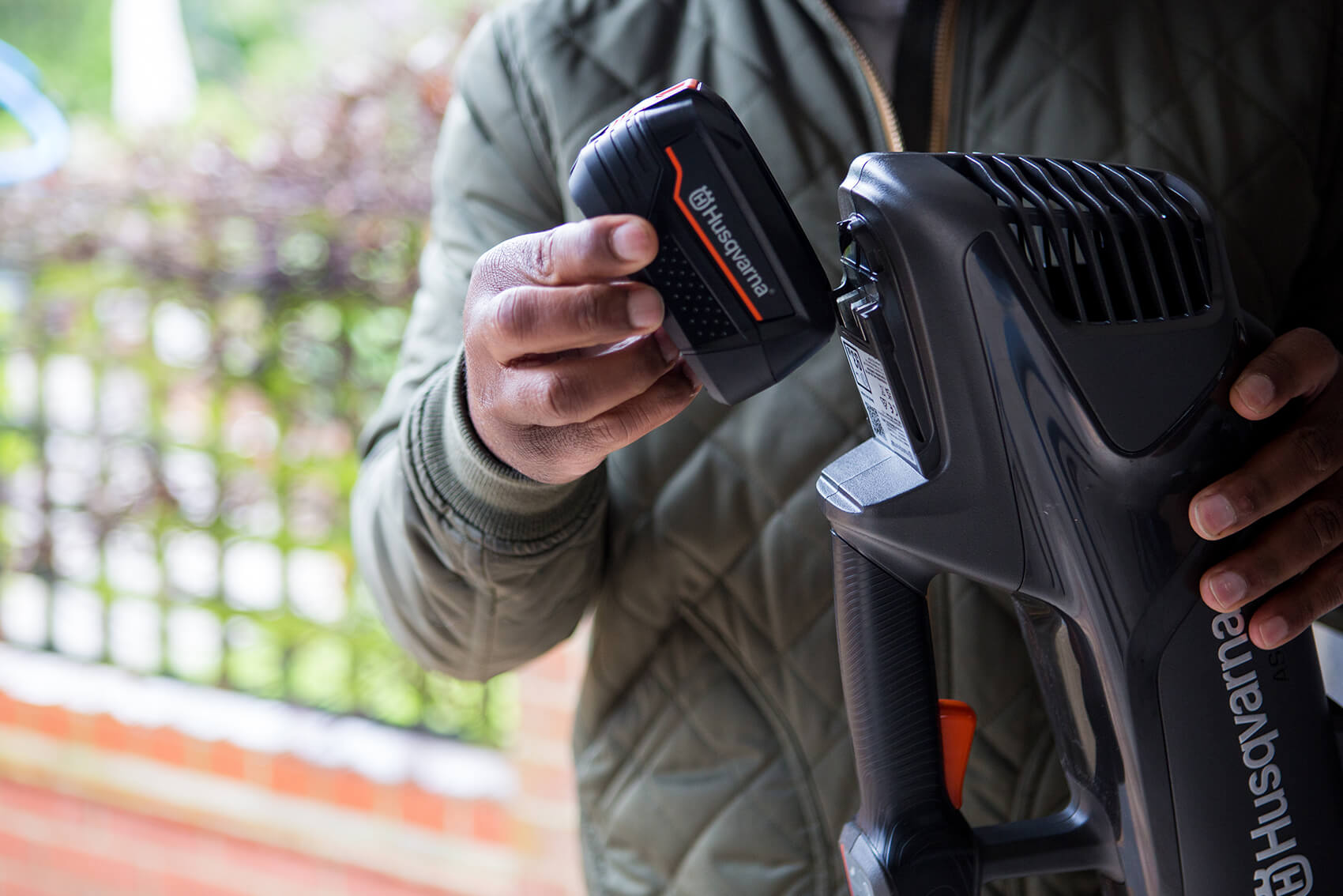 A man putting a battery into a hedge trimmer