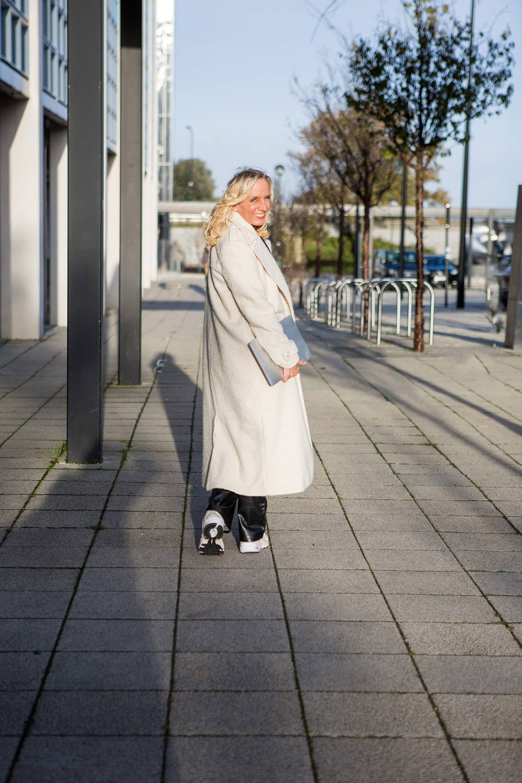 Woman in a white coat looking behind her and smiling