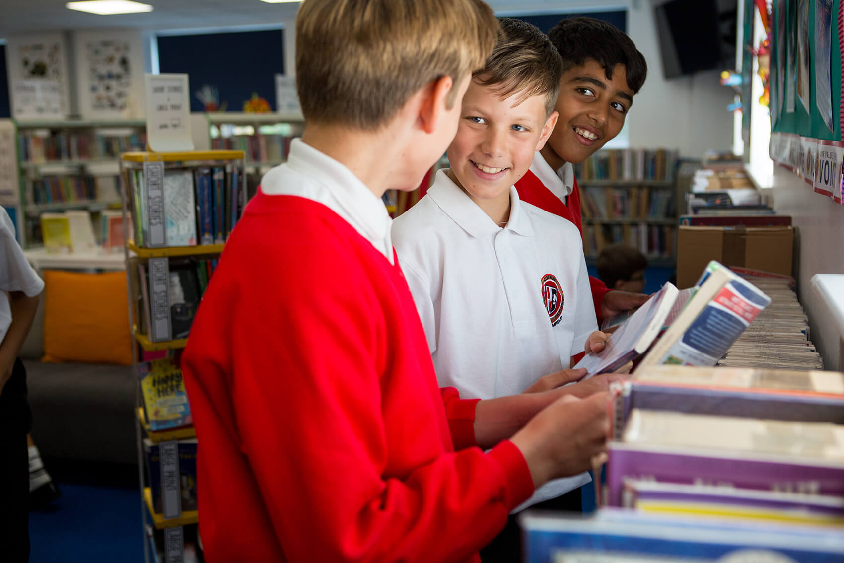 Three children discussing books in a library
