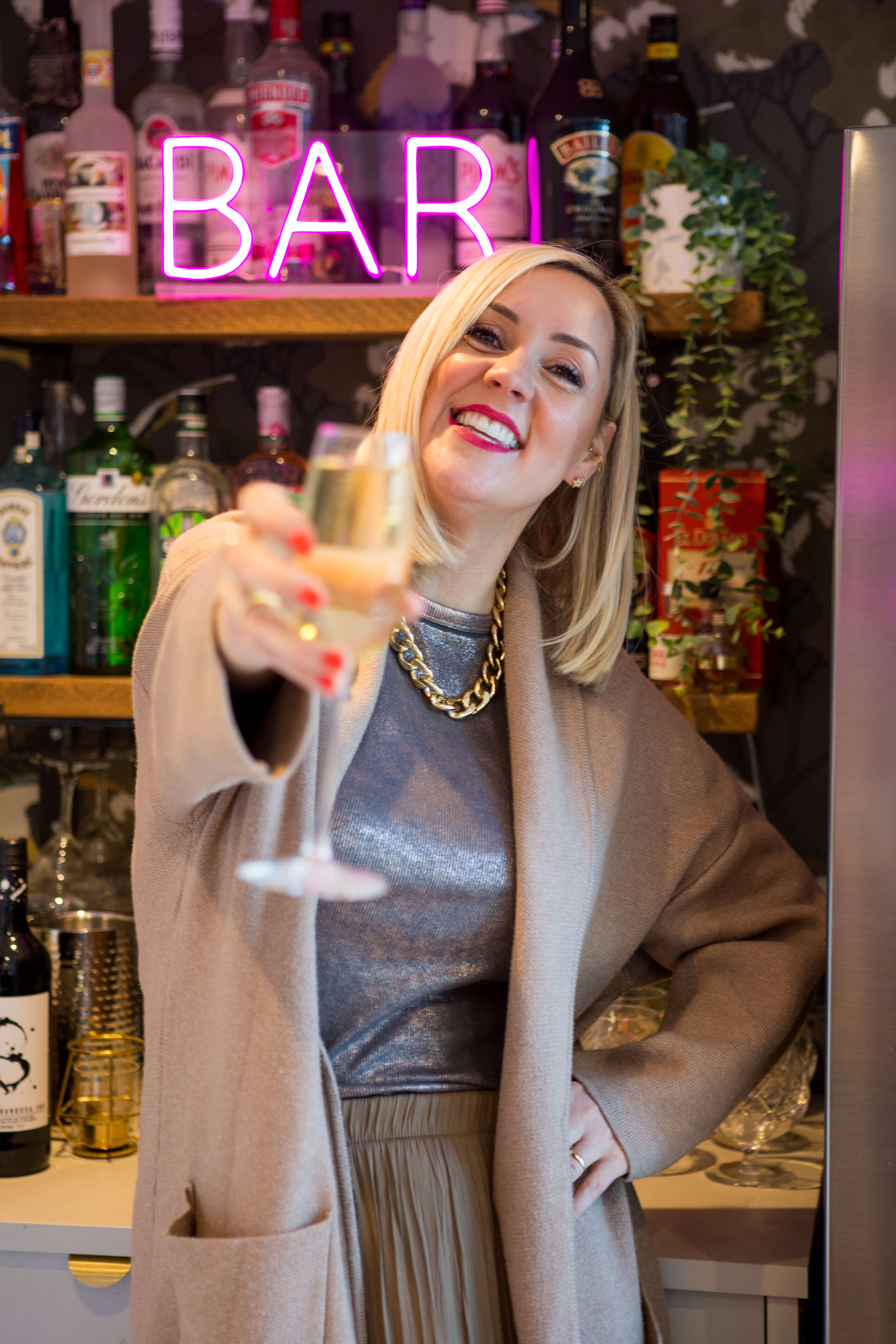 Woman in front of a bar holding a glass of champagne