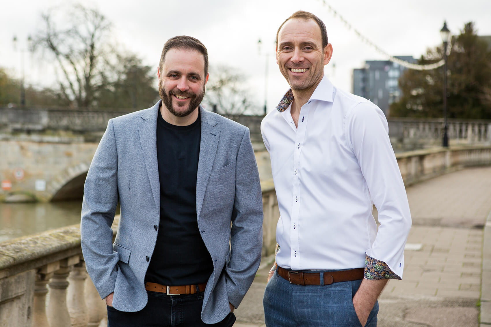 Two men smiling near a river