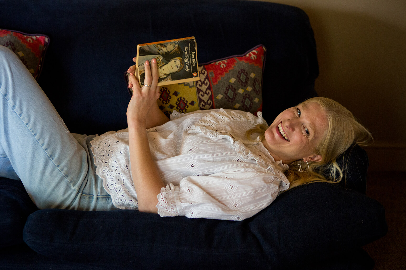 A woman laying on a couch with a book in her hands