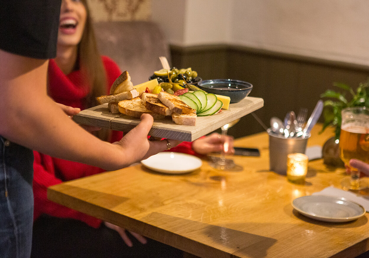 Server bringing food to a table of waiting guests
