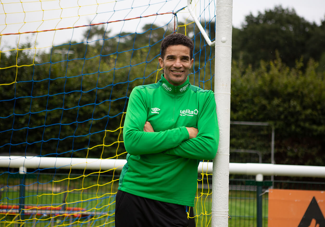 Male footballer leaning against the post of a goal