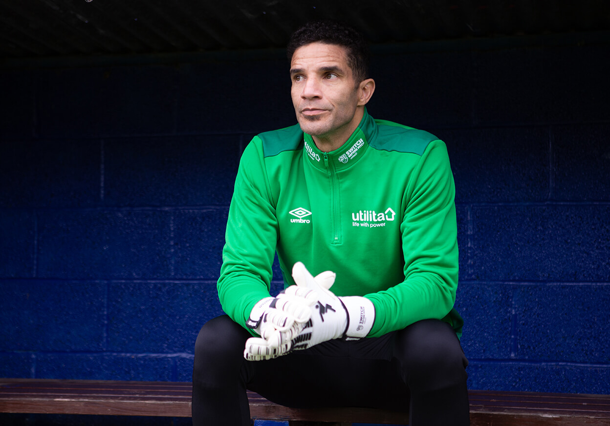 Male goalkeeper sat in the dugout with gloves on