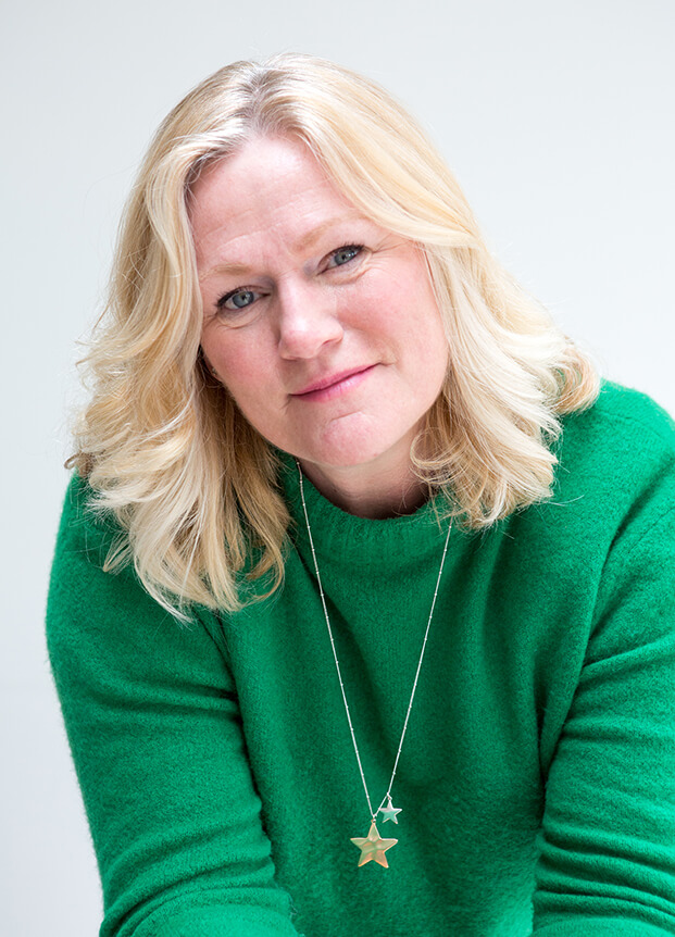 Woman in green top with star necklace looking into the camera