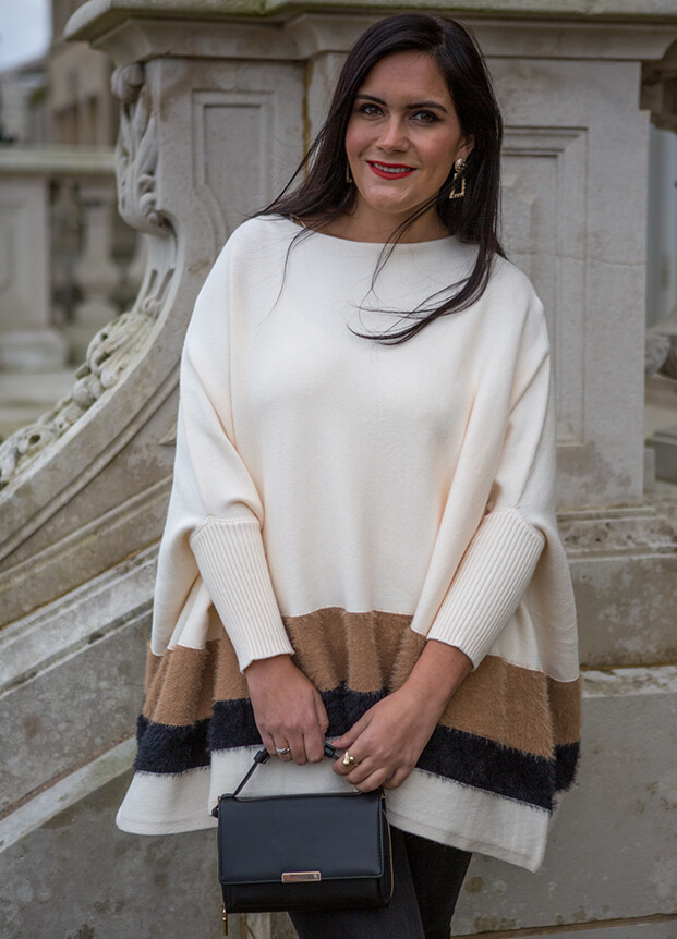 Woman in a large white jumper with a black handbag