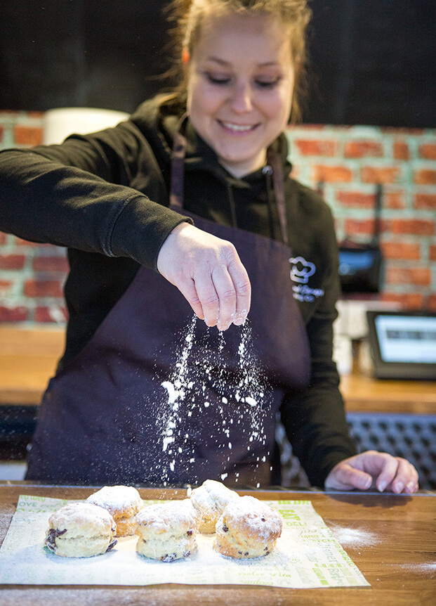 Woman sprinkling flour over some cakes