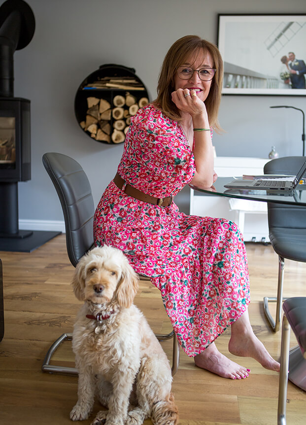Woman sat on a wooden chair with a dog by her side