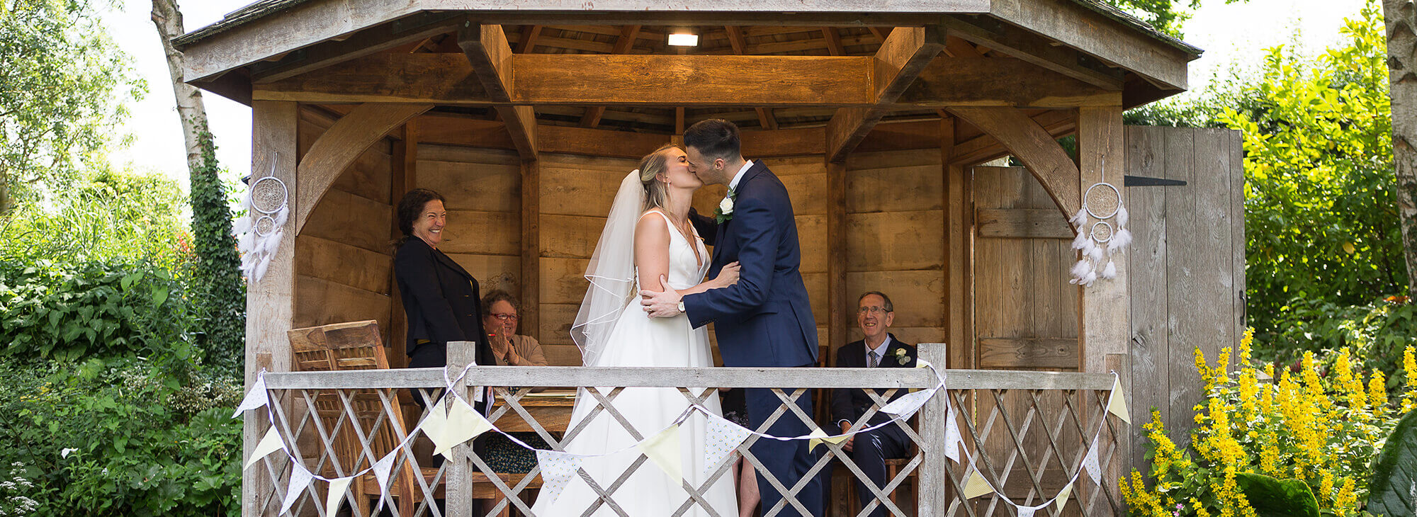 A couple kissing under a wooden out house