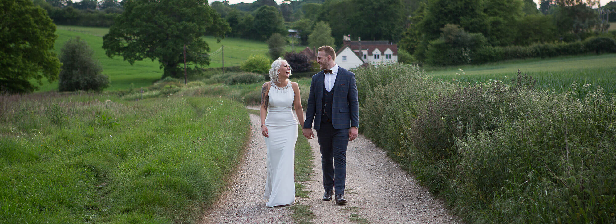 A newly married couple laughing happily walking down a dirt road