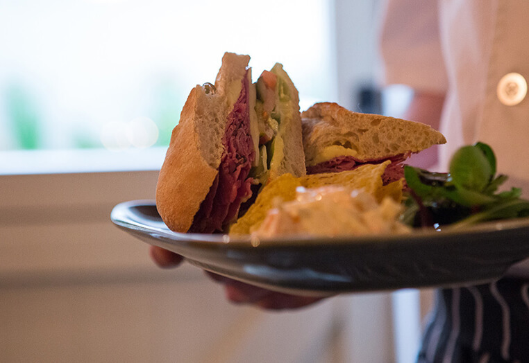 Waiter serving a sandwich, salad and crisp lunch