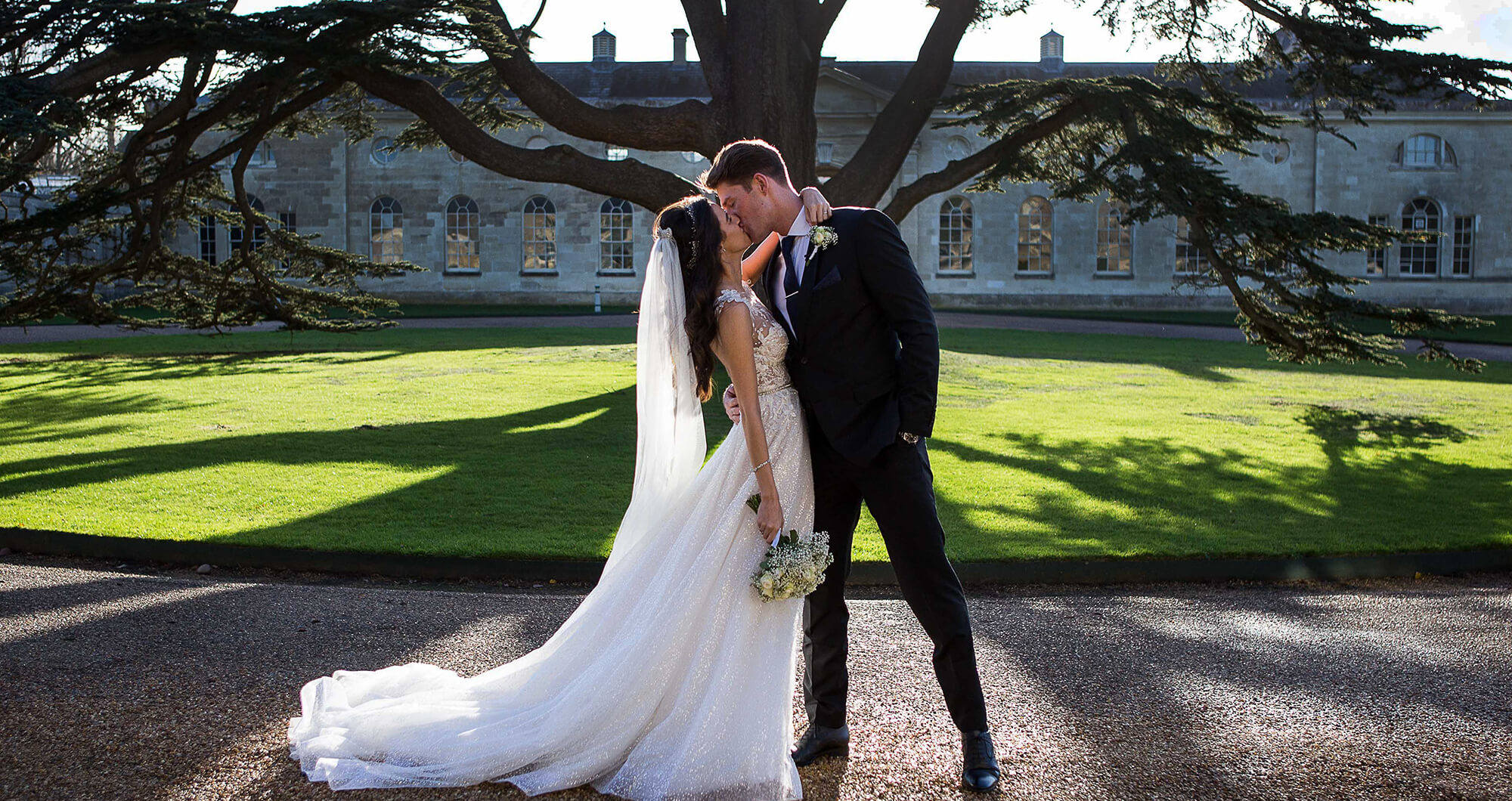 Newlyweds kissing in front of the sculpture gallery in Bedfordshire