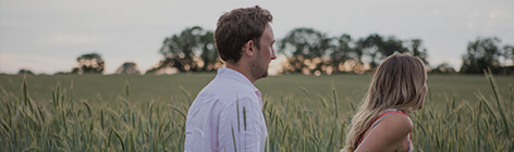 A couple running through a field holding hands