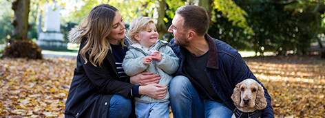 A man and woman kneel with a child and a dog