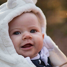 Baby in a hooded fleece smiling at the camera