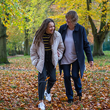 Two people laughing while walking through an autumn wood