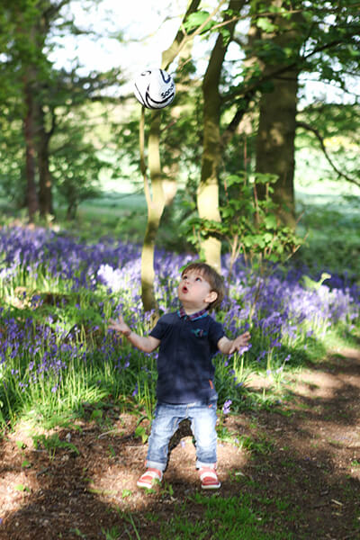 Young boy playing with football in woods