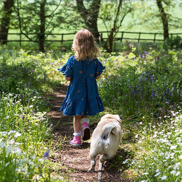 Young girl and dog following a garden path