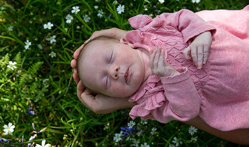 Baby being held above grass