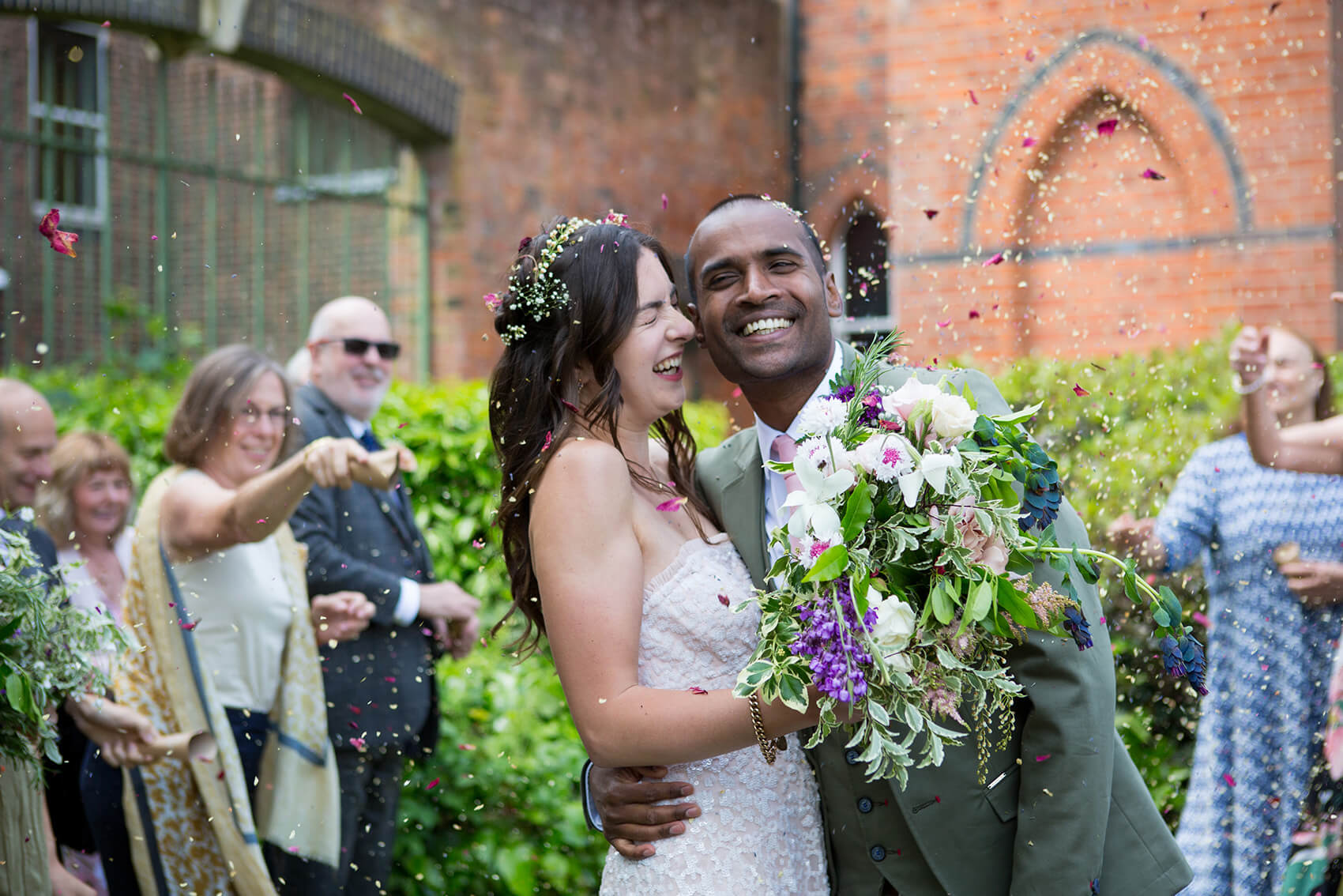 Bride and groom smiling while confetti is thrown on them