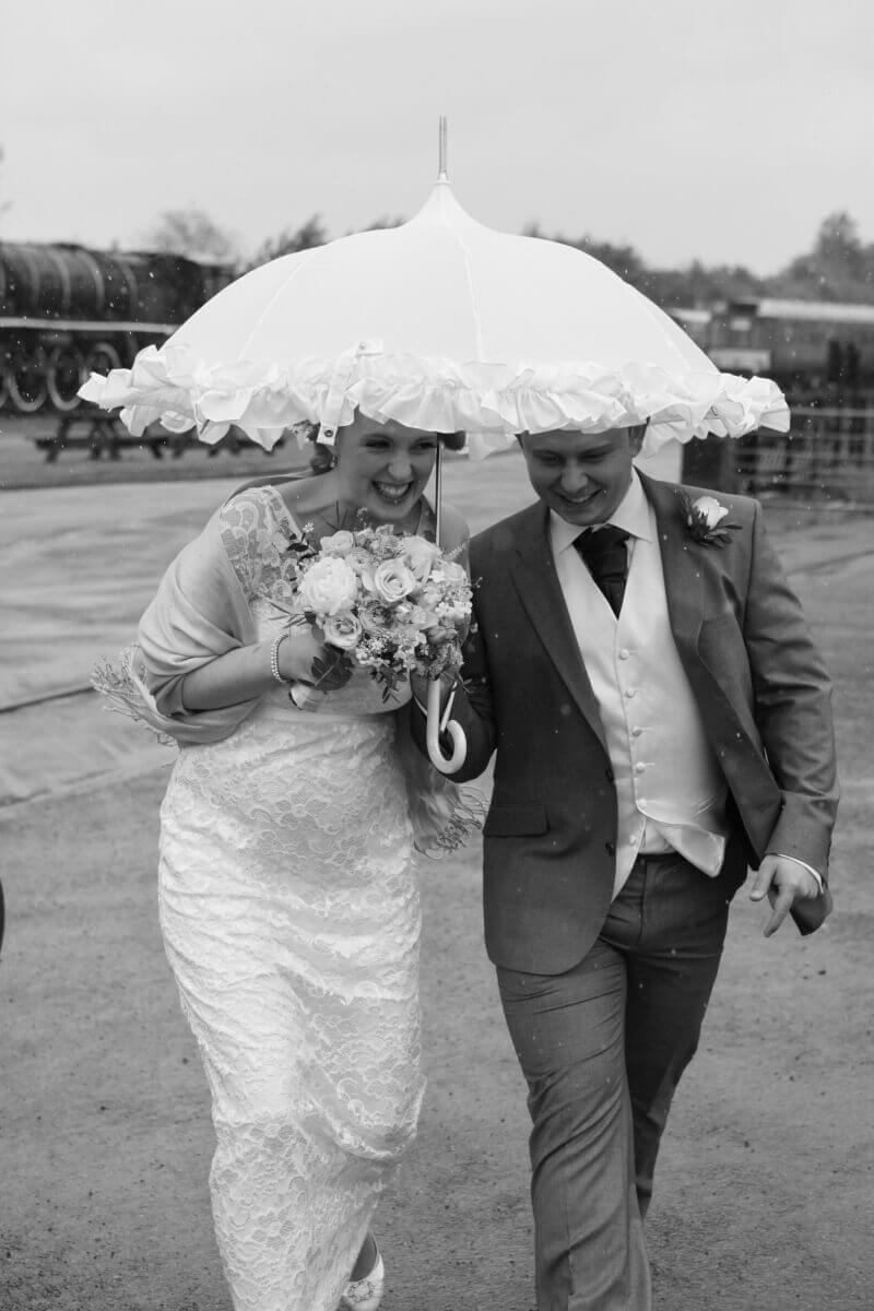 Bride and groom holding a white umbrella