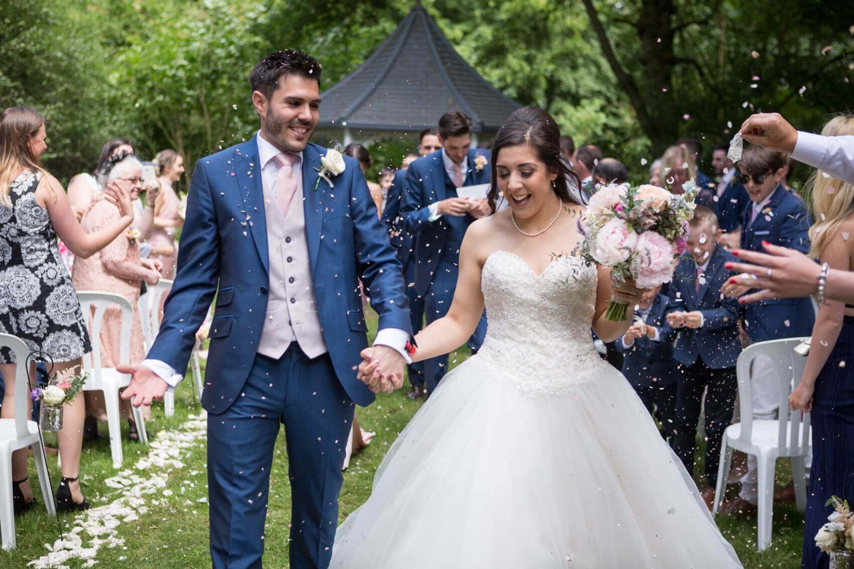 Outdoor wedding ceremony at Milling Barn Hertfordshire. Couple enjoying the confetti .